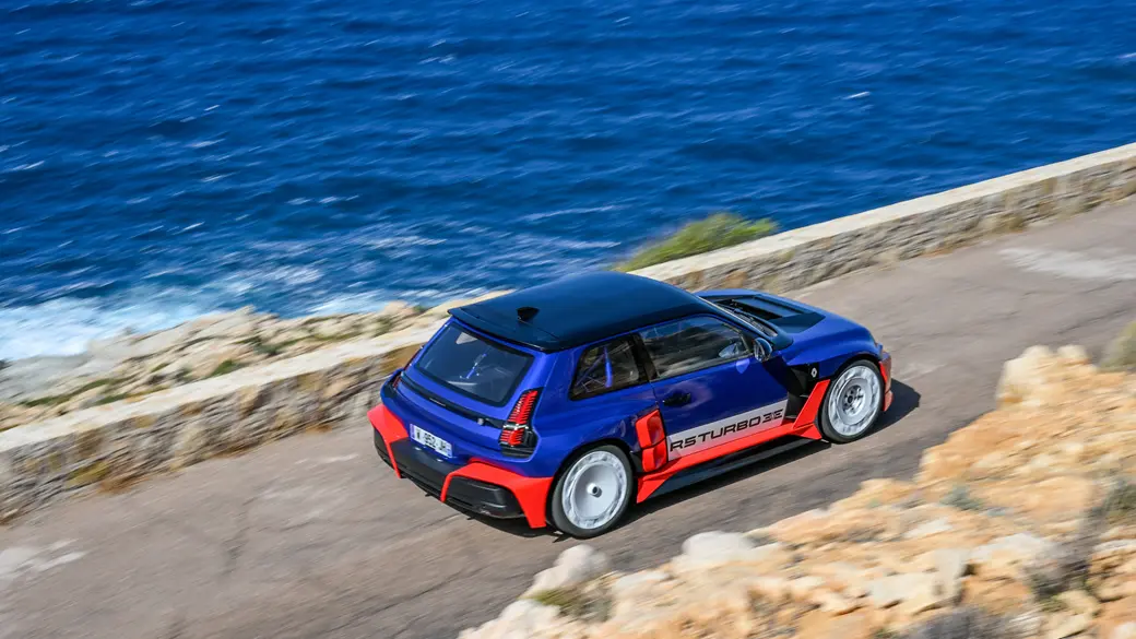 Renault 5 Turbo 3E with new livery racing along a coastal road.